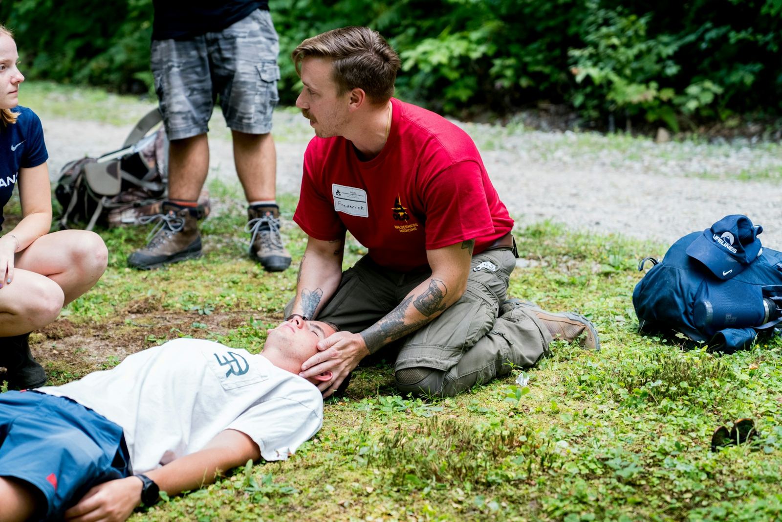 A first-aid class practicing on a person lying in the grass